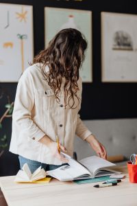 Kaboompics - Woman Turning Pages in Open Book at Desk