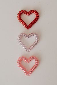 Kaboompics - Three Red and Pink Beaded Hearts Arranged Vertically on Beige Background
