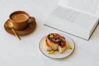Kaboompics - Coffee, Cinnamon Roll and Open Book on White Table