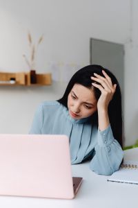 Kaboompics - Stressed Asian Woman Writing Notes with Her Head in Her Hand