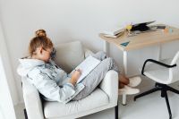 Kaboompics - Teenage Girl Writing Homework in Armchair by Study Desk