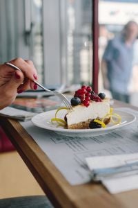 Kaboompics - Woman Enjoying Cheese Cake and a Coffee with Fruits in a Cafeteria
