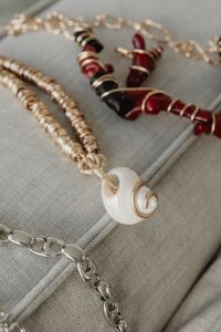 Kaboompics - Layered Gold and Beaded Necklaces on a Sofa