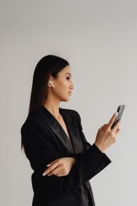 Kaboompics - Asian Woman Checking a Smartphone with Wireless Earbuds
