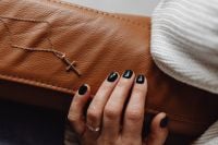 Kaboompics - Hand Touching a Gold Cross Necklace on Brown Leather