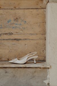 Kaboompics - White high-heeled open-back pumps with front embellishment - Pointed toe - Ankle strap