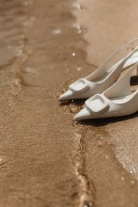 Kaboompics - White Pointed-Toe Buckle Mules on Wet Beach Sand