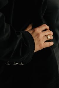 Kaboompics - Close-Up Hand Wearing Gold Ring on Black Blazer