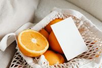 Kaboompics - Angled Branding Card Resting on Fresh Oranges in a Cotton Shopping Bag