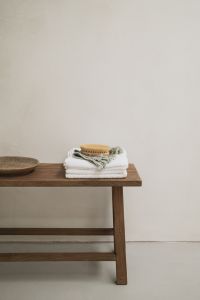 Kaboompics - Wooden Bench with Towels and Body Brush Against White Wall