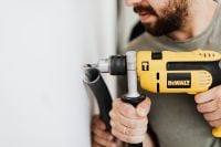 Kaboompics - Home Repair Worker Holding a Yellow Power Drill beside a White Wall, Close-Up Renovation