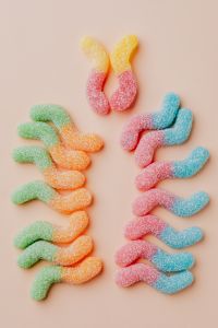 Kaboompics - Pastel Sugar-Coated Gummy Worms on a Pale Pink Background
