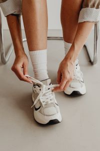 Kaboompics - Female Hands Pulling Shoelaces on a Chunky White Sneaker