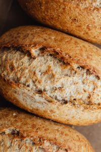 Kaboompics - Rustic Whole Grain Bread Loaf with Cracked Flour-Dusted Crust, Macro Bakery Photo