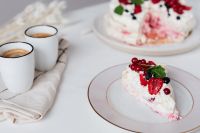 Kaboompics - Pavlova Cake Slice in Foreground with Espresso Cups and the Whole Cake