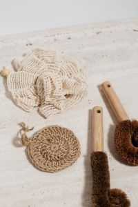 Kaboompics - Reusable Bath Accessories: Mesh Bag, Jute Scrubber and Bamboo Body Brushes on Limestone