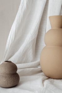 Kaboompics - Beige Sculptural Vase and Speckled Pot with Draped White Linen