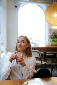 Blonde Woman Enjoying Coffee and Brunch in a Bright Cafe