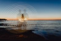 Kaboompics - Light painting. The man waving fairy lights at the sea at sunset.
