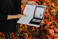 Kaboompics - Close-Up of Hands Holding an Open Design Book with Autumn Foliage Softly Blurred Behind