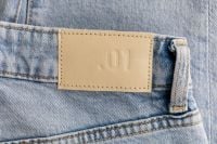 Kaboompics - Wide Back Waistband of Light Blue Jeans with Embossed 01 Patch and Topstitching