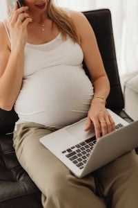 Kaboompics - Pregnant Woman on a Phone with Laptop in a Chair
