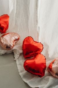 Kaboompics - Metallic Red and Blush Heart Balloons Against White Draped Fabric