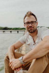 Kaboompics - Casual Man in Eyeglasses Seated on a Dock, Vertical Portrait with Digital Wristwatch