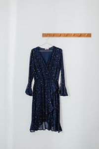 Kaboompics - Minimal Product Display of a Navy Polka Dot Dress on a Wooden Hanger
