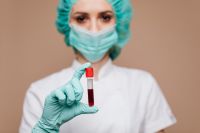 Kaboompics - Masked Healthcare Worker Holding a Red-Capped Blood Sample Tube, Medical Testing Campaign Portrait