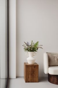 Kaboompics - Minimalist Floral Interior with White Vase, Wooden Pedestal and Armchair