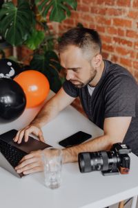 Kaboompics - Close-Up of MacBook, DSLR Camera and Glass on Photographer's Desk
