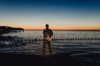Kaboompics - Light painting. The man waving fairy lights at the sea at sunset.