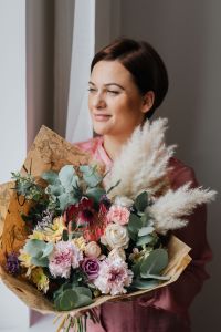 Kaboompics - Smiling Woman with a Kraft-Paper-Wrapped Floral Bouquet