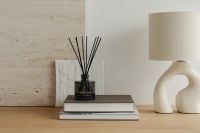 Kaboompics - Reed Diffuser on Stacked Books beside a Sculptural Ceramic Lamp