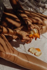 Kaboompics - Close-Up of Hands Peeling an Orange under Leaf Shadows