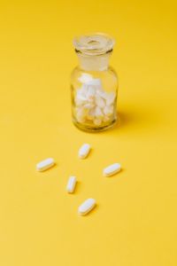 Kaboompics - Yellow Medicine Bottle with Scattered White Tablets