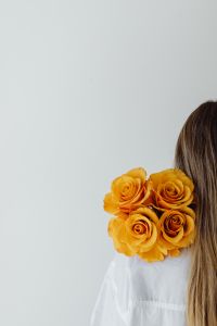 Kaboompics - Woman Holding Orange Roses over Her Shoulder for Floral Portrait Campaigns
