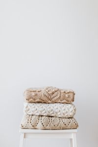 Kaboompics - Cream Cable-Knit Sweaters Arranged on White Stool