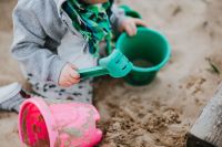 Kaboompics - Close-Up of a Toddler Playing with a Green Sand Scoop and Pink Bucket