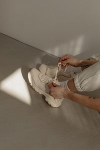 Kaboompics - Woman Tying Neutral Sneakers in a Minimalist Interior