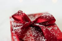 Kaboompics - Macro Detail of a Snow-Dusted Red Satin Bow on a Christmas Gift Box