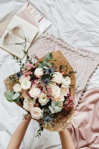 Kaboompics - Floral Arrangement With Book and Eyeglasses on White Bedding