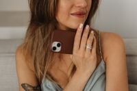 Kaboompics - Ringed Hand Holding a Smartphone Against a Woman’s Shoulder, Close-Up