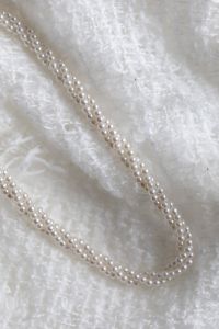 Kaboompics - Long Pearl Necklace Looped on a White Textured Blanket