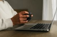Kaboompics - Close-Up of Photographer Holding Camera Beside Laptop
