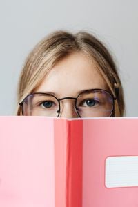 Kaboompics - Teenage Student Reading Behind Pink School Notebook