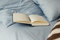 Kaboompics - Open Book on Soft Blue Bed With Copy Space