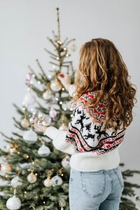 Kaboompics - Woman Reaching Toward a Christmas Tree in a Festive Knit Sweater