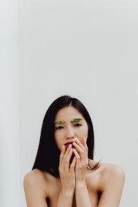 Kaboompics - Vertical Minimal Portrait of Woman Covering Mouth with Both Hands and Green Brow Styling